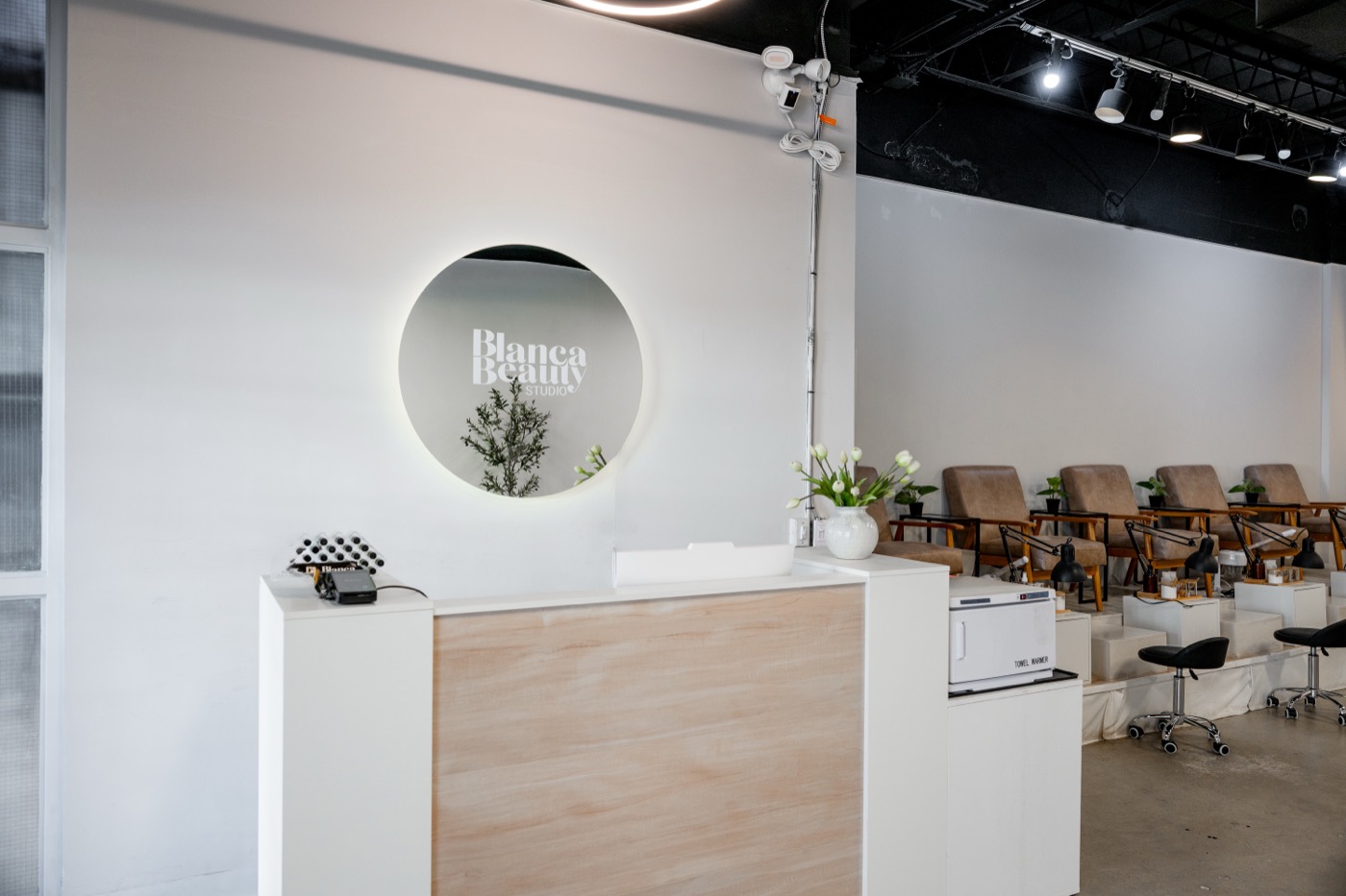 Reception desk with the circular backlit Blanca Beauty mirror and an olive plant